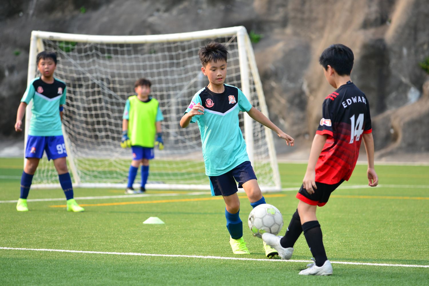 Young football players competing for the ball on an outdoor pitch